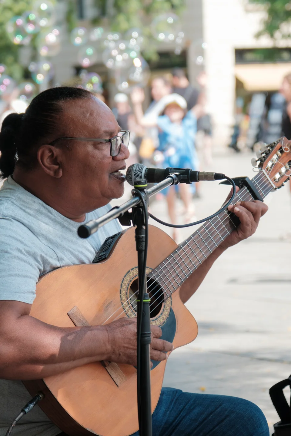Street musician playing guitar among floating bubbles