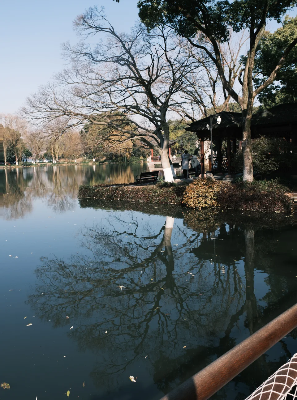 Lakeside pavilion and trees reflected in still water
