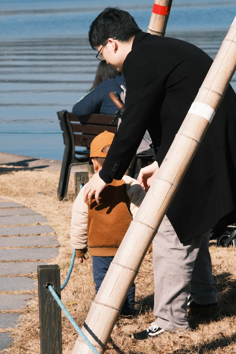 An adult leaning toward a child beside the lake