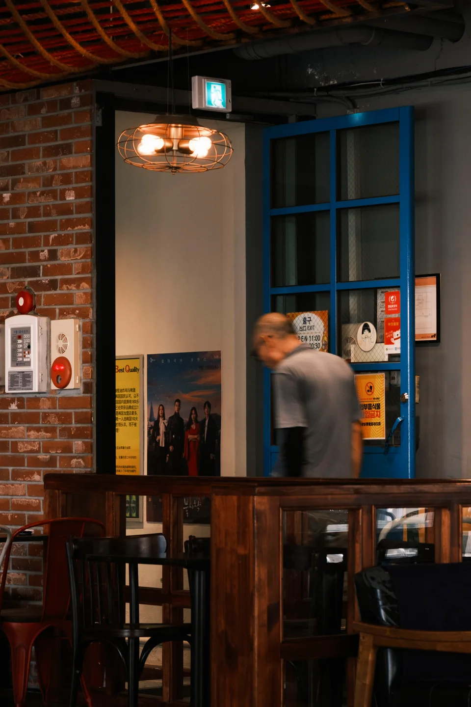 A person passing a blue doorway under warm indoor light